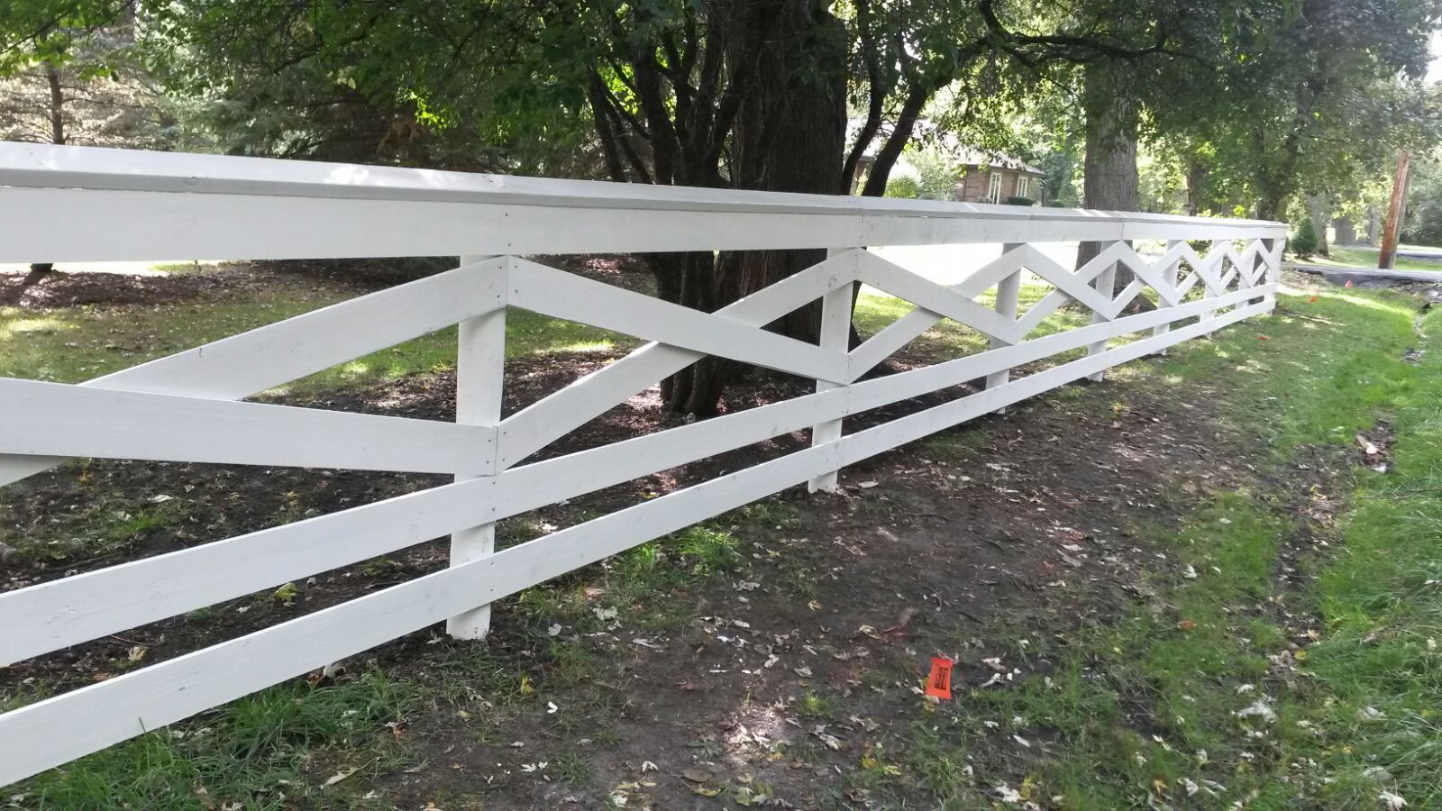White crossed-rail fence beside a garden bed.