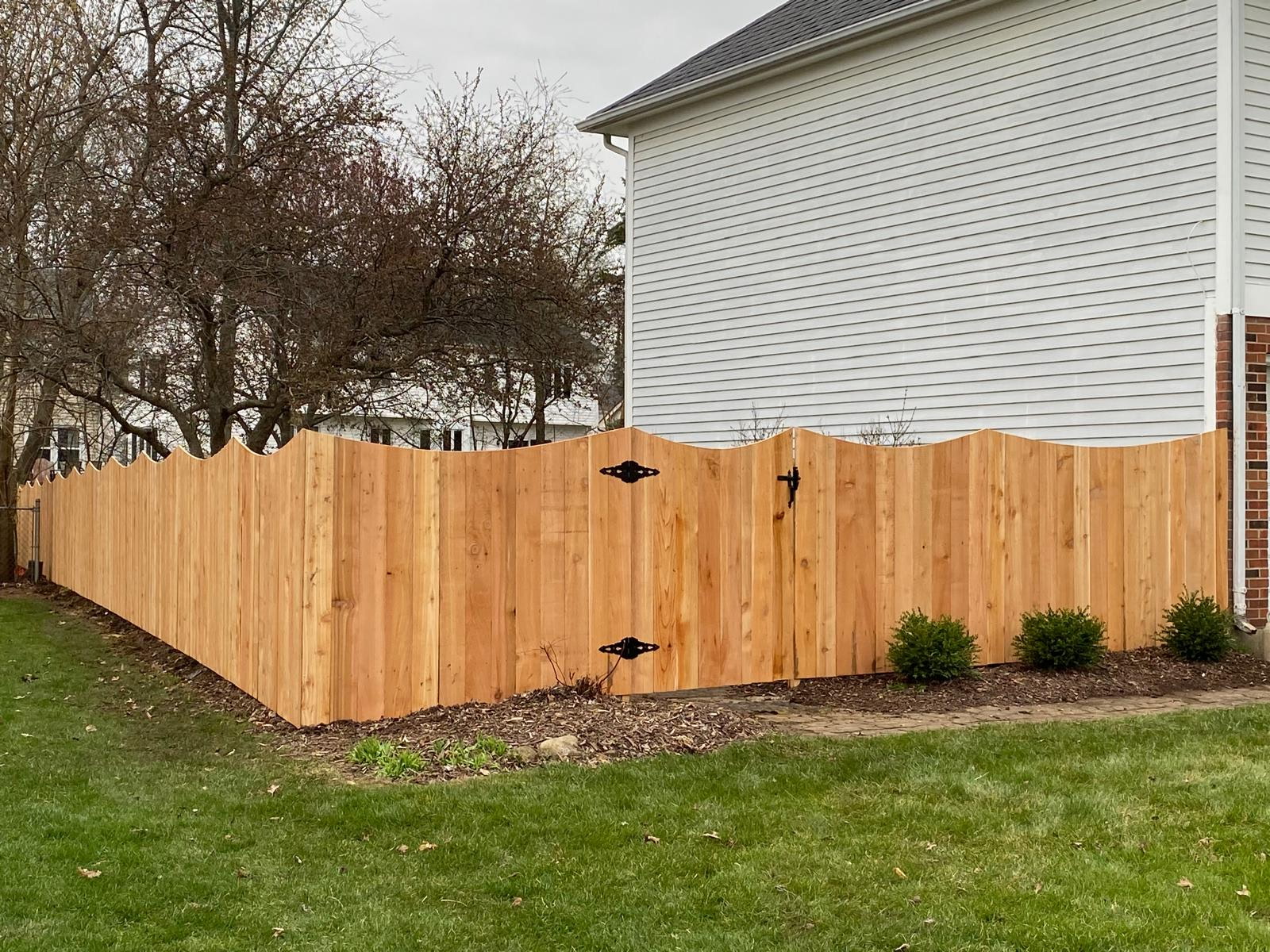 Scalloped wood privacy fence beside a house.