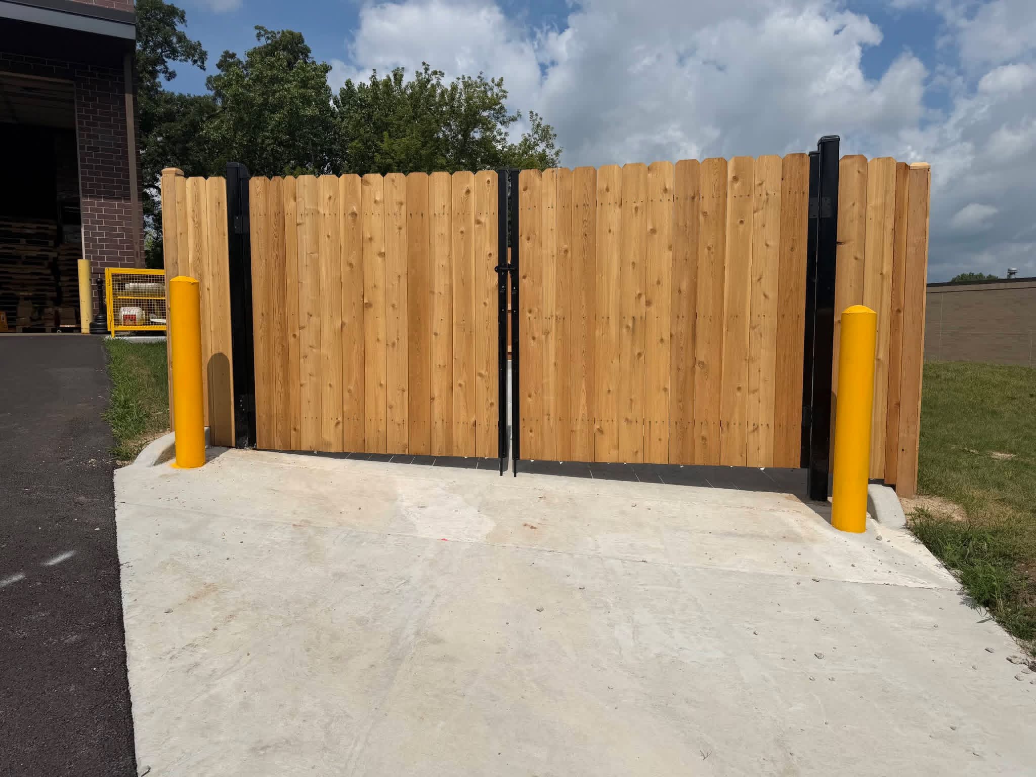 Wood enclosure gates between protective yellow posts.