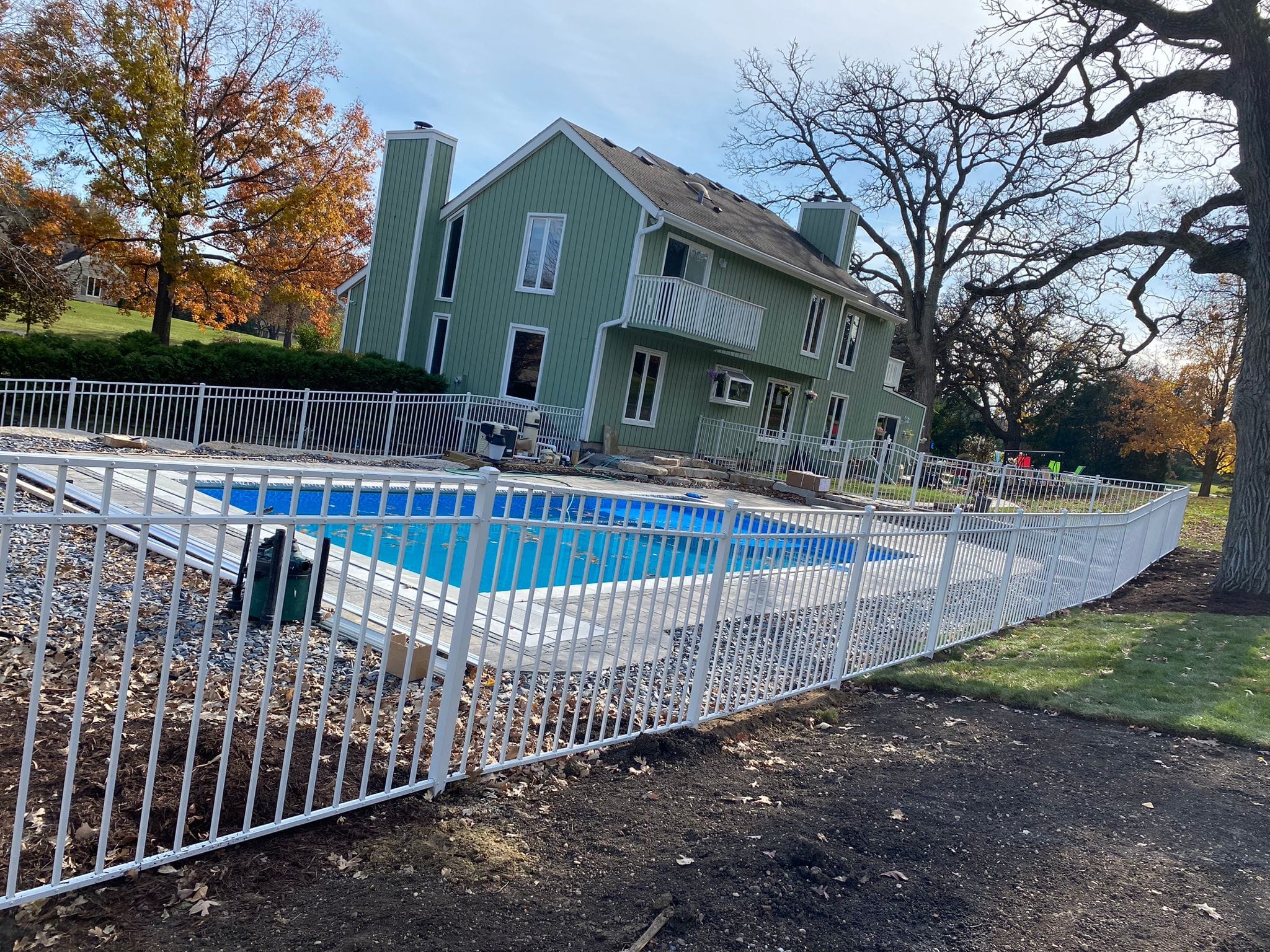 White metal fence surrounding a backyard pool.
